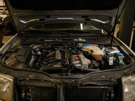 Close-up of a car engine details, motor of a car with open hood. Auto service, maintenance, warranty repair concept in car repair workshop photo