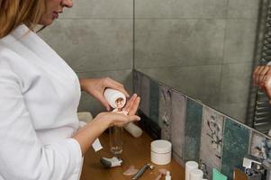 Close-up of a beautiful pregnant young woman taking pills with beauty and health supplements, having diet nutrition, standing in the home bathroom photo