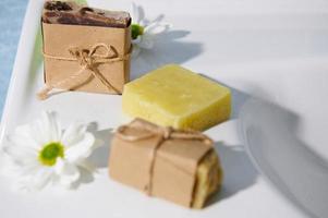 Still life with natural organic soap bars, wrapped in eco paper and tied with linen rope on white ceramic washbasin photo