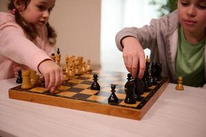 Soft focus on the hands of a happy boy and little girl playing chess in home interior. Smart intellectual board games for kids, logic development, education concept. Chess game for clever mind photo