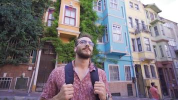 jovem homem caminhando dentro Turística lugar. jovem homem caminhando dentro Turística Lugar, colocar com colorida casas. video