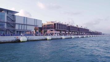 stad en zee visie. modern gebouwen en druk mensen wandelen. menigte mensen wandelen door de zee in de stad. video