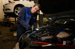 Technician automotive checking car in the garage. Auto mechanic working with engine in garage, car service technician repairing customer care at automobile service center. photo