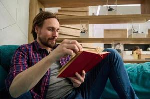 Close up of young Caucasian man reading book at home. Education, study, knowledge and erudition concept photo