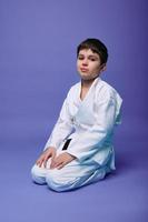 europeo Adolescente chico - aikido combatiente en un blanco kimono durante el práctica de oriental marcial letras. foto