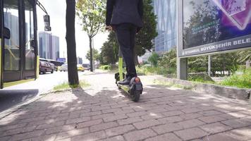 pieds de une homme d'affaire sur un électrique scooter. homme d'affaire disques électrique scooter dans le milieu de le ville. video
