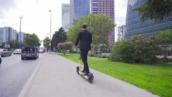 empresario montando e-scooter en el ciudad. el empresario lo hace no daño el ambiente mientras montando el eléctrico scooter. video