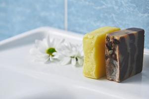 Still life. Homemade natural organic soap bars and chamomile flowers on white wash basin. Body care, home spa, hygiene photo