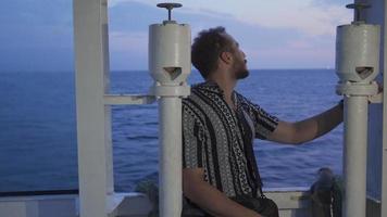 el hombre mirando fuera a mar desde dentro el barco. el joven hombre de viaje en el Embarcacion relojes el mar. video