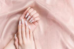 A woman's hands with a manicure on them, the nails are painted in a white color. photo