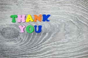 Closeup shot of colorful text thank you on gray wooden background photo