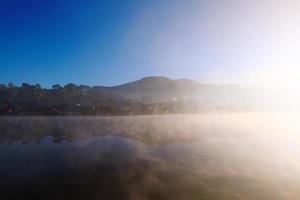 Beautiful landscape heaven of mist and fog over the lake and sunrise shining with blue sky reflection on the water surface at Hill tribe village on mountain in Thailand photo