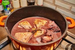 Chicken marinated in red wine with rosemary in saucepan on gas stove photo