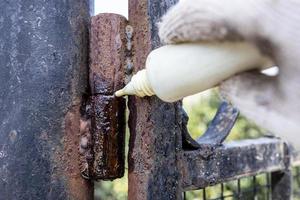 lubricating of rusty gate hinge with oil outdoors photo