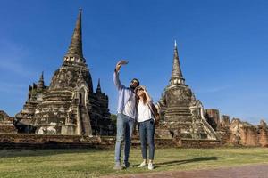 un par de turistas extranjeros toman una foto selfie en el templo wat phra si sanphet, ayutthaya tailandia, para viajes, vacaciones, vacaciones, luna de miel y concepto de turismo