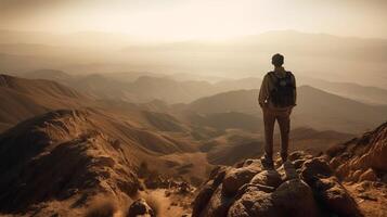 A man stands on a mountain top looking at the mountains and the desert. photo