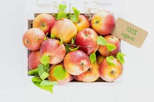 Natural red apples in wooden box with label with text 100 percent organic photo