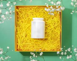 Yellow gift box with vitamins or supplements on green background photo