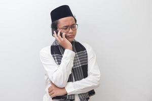 Portrait of young Asian muslim man making a phone call. Isolated image on white background photo