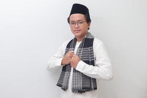 Portrait of young Asian muslim man standing with cool pose and holding his sarong. Isolated image on white background photo