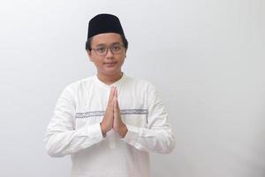 Portrait of young Asian muslim man showing apologize and welcome hand gesture. Isolated image on white background photo