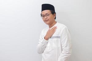 Portrait of young Asian muslim man placing hand on heart, feeling very grateful. Isolated image on white background photo