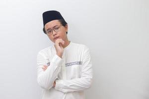 Portrait of young Asian muslim man thinking about question with hand on chin. Isolated image on white background photo