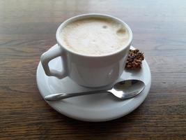 taza de café en un de madera mesa. blanco taza con platillo y cuchara foto