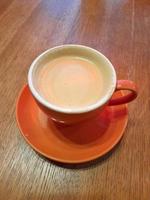 naranja taza de café en un de madera mesa. café en un taza foto