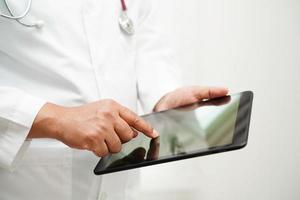 Asian woman doctor holding mobile phone or tablet for search method of treatment patient in hospital. photo