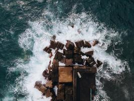 Drone view of waves crashing at Seixal Pier in Madeira, Portugal photo