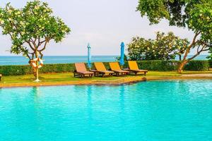 chair pool  or bed pool and umbrella around swimming pool with sea background photo