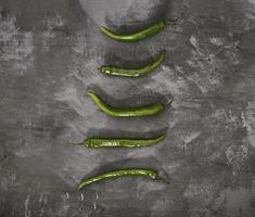 Green chili pepper on a concrete slab. Fresh green paper on the dark gray background. photo