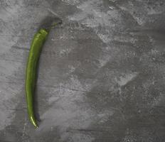 Green chili pepper on a concrete slab. Fresh green paper on the dark gray background. photo