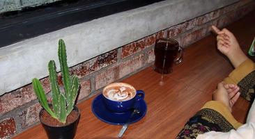 café en un azul taza, en un de madera mesa y un pequeño cactus foto