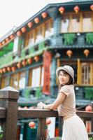 woman traveler visiting in Taiwan, Tourist with hat sightseeing in Jiufen Old Street village with Tea House background. landmark and popular attractions near Taipei city . Travel and Vacation concept photo