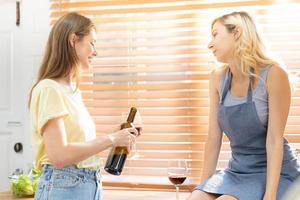 hembra Pareja preparando comida juntos y Bebiendo vino. lesbiana pareja, champán y lgbtq con contento sonrisa, amor y Cocinando en cocina y hospedaje un fiesta en hogar. foto