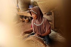 old female craftsmen while weaving bamboo into baskets photo