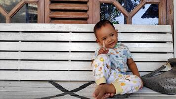 Cute little boy sitting on wooden chair photo