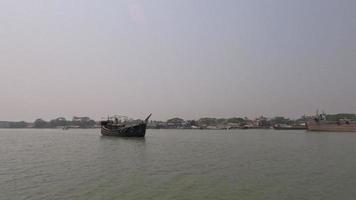 A beautiful Asian wooden trawler going through the river. Scenic rural area footage with a river, blue sky, and port area. Southeast Asian waterway with a water boat. Small wooden fishing trawler. video