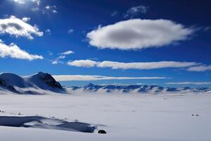 Vast expanse of frozen tundra with snow-covered mountains in the distance and a clear blue sky overhead. photo