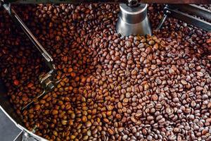 Freshly roasted aromatic coffee beans over a modern coffee roasting machine. photo