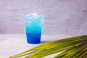 Blue Hawaiian drink in a plastic glass and coconut leaves. photo