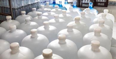 mucha agua galon blanco. galón con tapas blancas. planta de embotellado línea de embotellado de agua para procesar y embotellar agua potable en botellas. negocio de agua potable foto