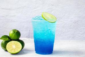 Blue Hawaiian drink in a plastic glass and lime on white background photo