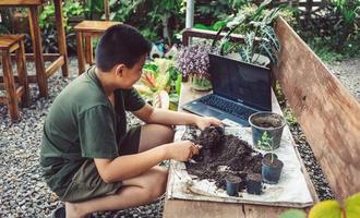 Boy learns to grow flowers in pots through online teaching. shoveling soil into pots to prepare plants for planting leisure activities concept photo