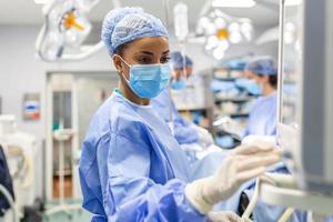 Concentrated Surgical team operating a patient in an operation theater. Well-trained anesthesiologist with years of training with complex machines follows the patient throughout the surgery. photo