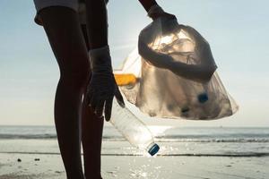 ahorrar agua. los voluntarios recogen basura en la playa y las botellas de plástico son difíciles de descomponer para evitar dañar la vida acuática. tierra, ambiente, planeta verde, reducir el calentamiento global, salvar el mundo foto