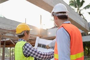 inspector or engineer is inspecting construction and quality assurance new house using a blue print. Engineer or architects or contactor work to build the house before handing it over to the homeowner photo