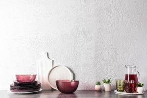 fashionable modern tableware in burgundy color and a jug of grape juice on the kitchen countertop with a copy of the space. kitchen background. photo